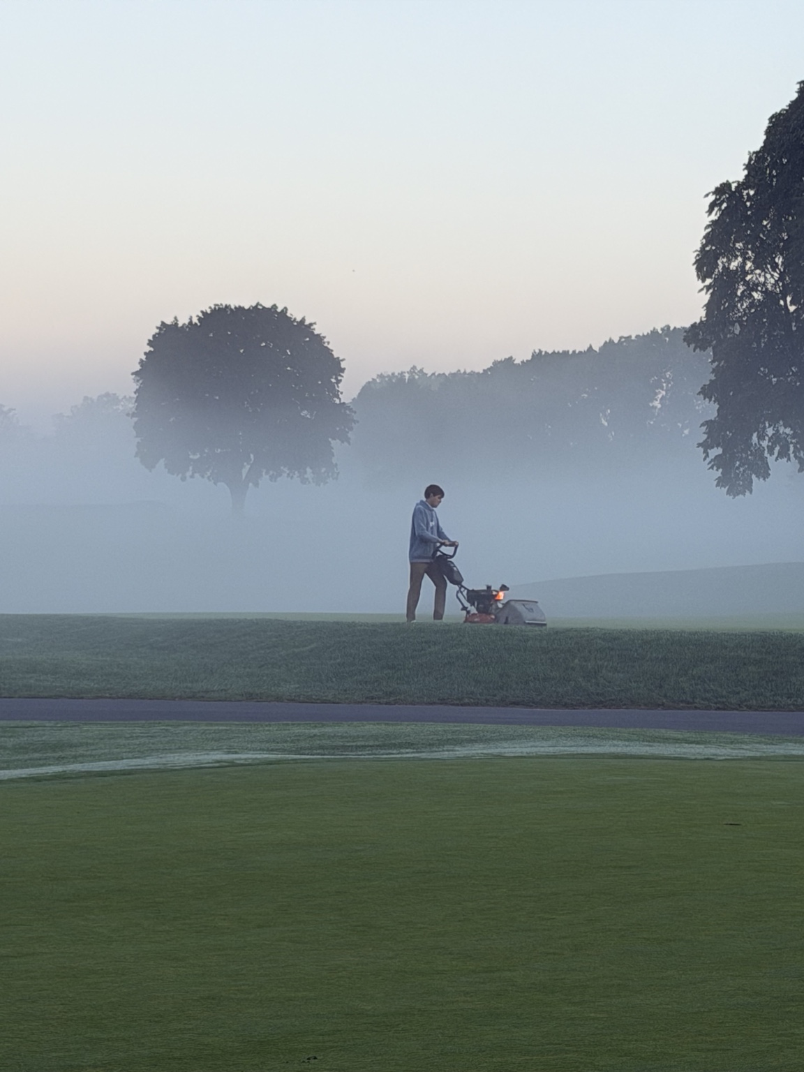 Grounds crew member working on a foggy golf course