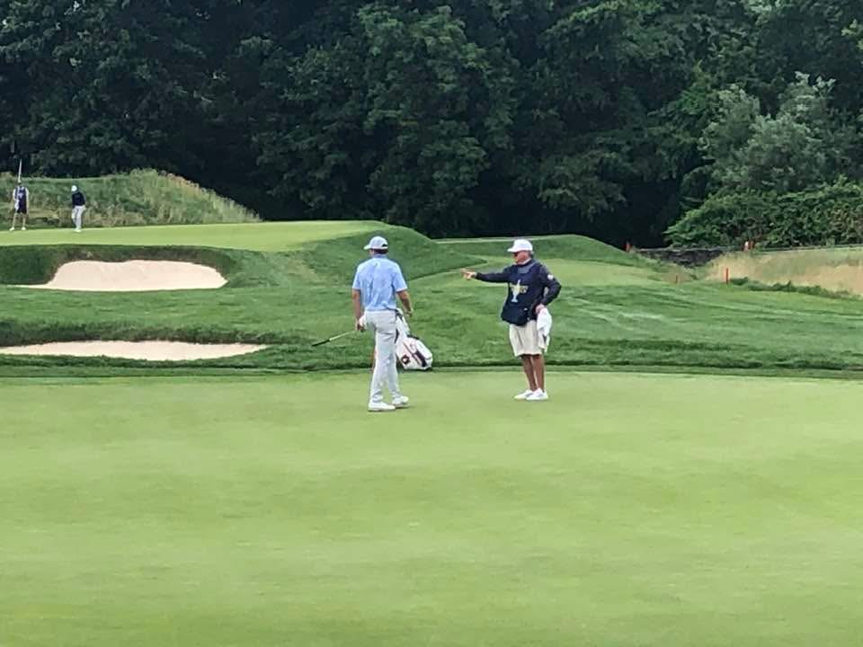 A caddy guiding a player on the putting green